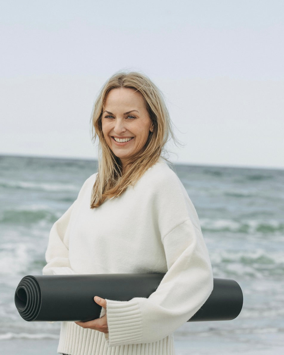 Women walking on the beach with her yoga mat